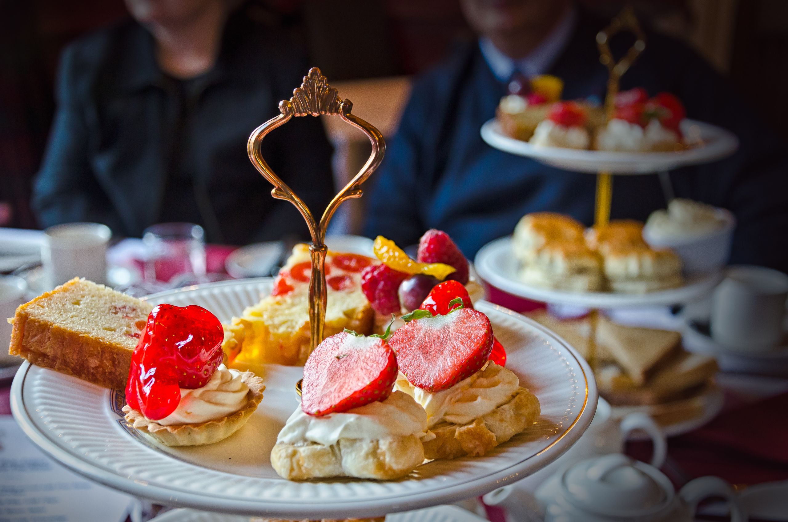 A delicious arrangement of desserts and scones on a tiered stand during afternoon tea.